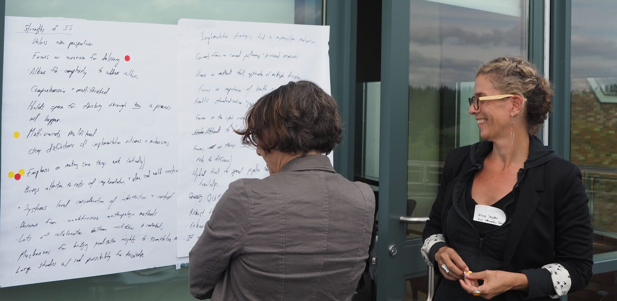 Pat Arean and Jaime Synder reading giant post it notes at our 2019 Pre-SIRC Workshop